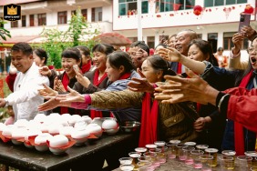A documentary photograph captures a lively and cheerful scene in a rural area of Weng'an County, Guizhou Province, China. The image shows relatives and friends engaging in a traditional door-blocking game to welcome the groom.
